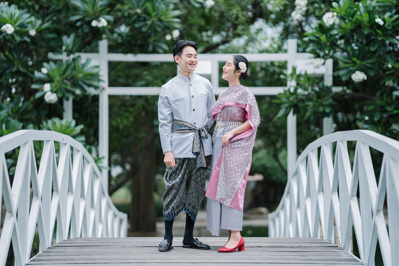 Wedding couple in traditional Thai dress at The Leela Resort & Spa Pattaya's signature white bridge